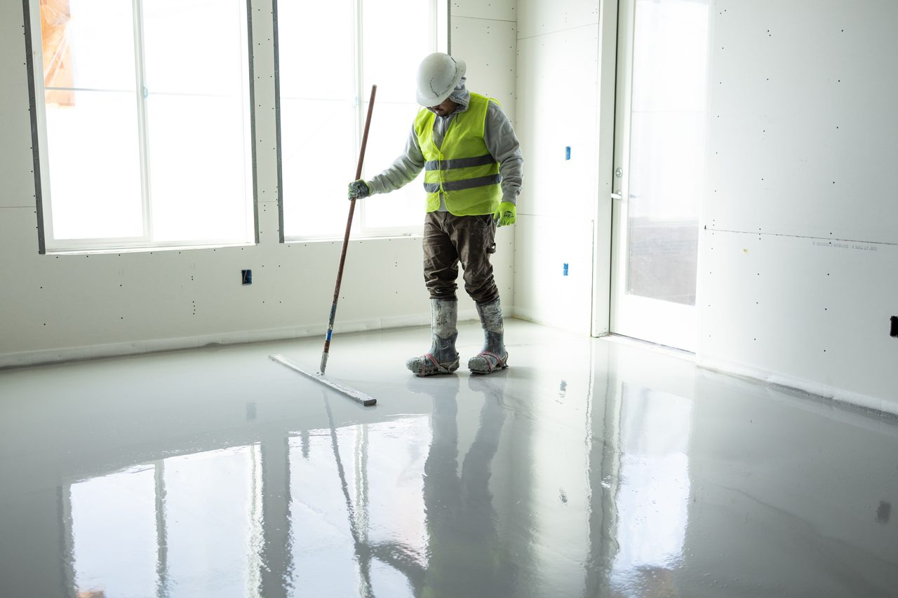 Finisher smoothing the wet floor by bright windows