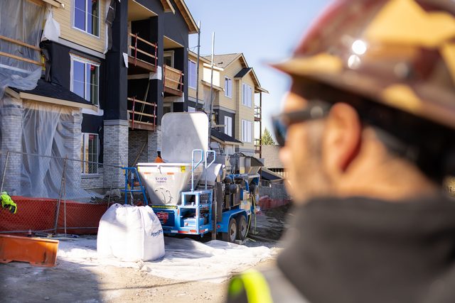 Crew member overlooking the Smart Batch GC-1 and materials in front of a multifamily building