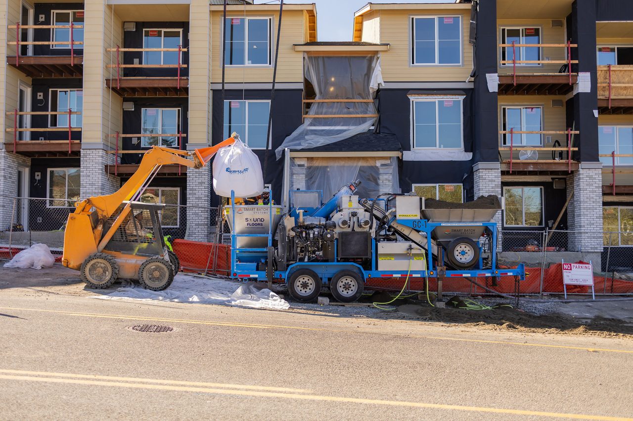 Smart Batch GC-1, supersack, and skid steer loading before a three-story multifamily building